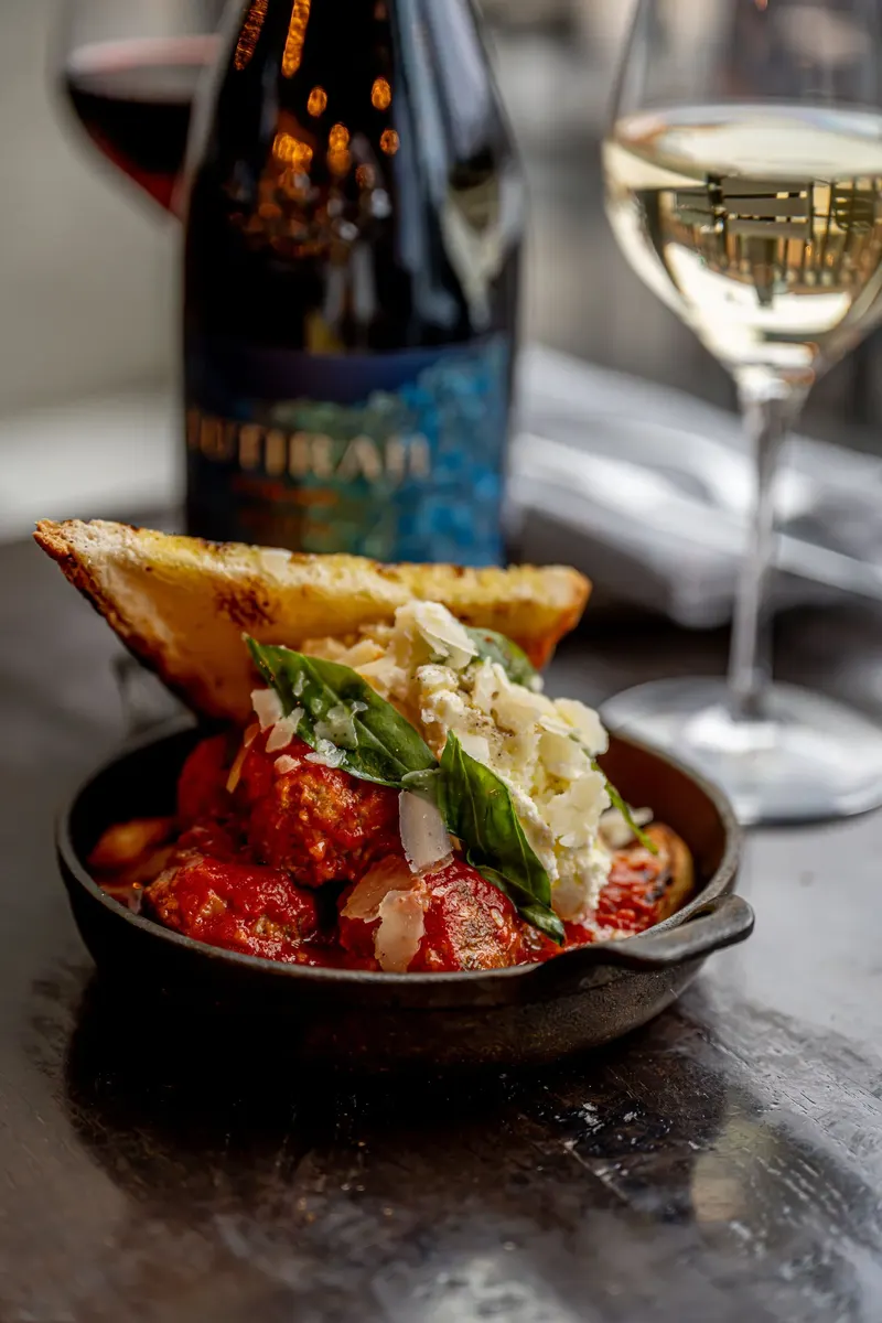 Toasted bread topped with tomato in a skillet beside a wine bottle