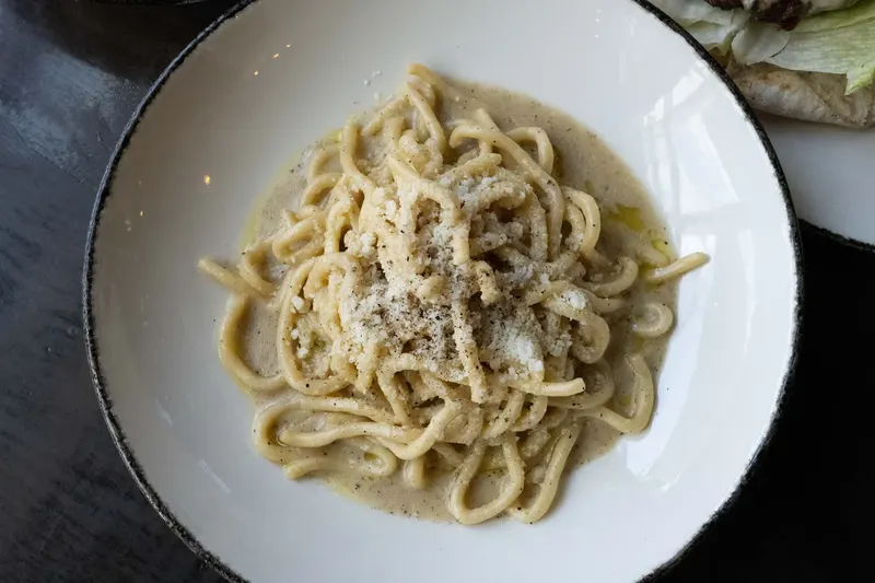 A bowl of pasta finished with pepper and cheese
