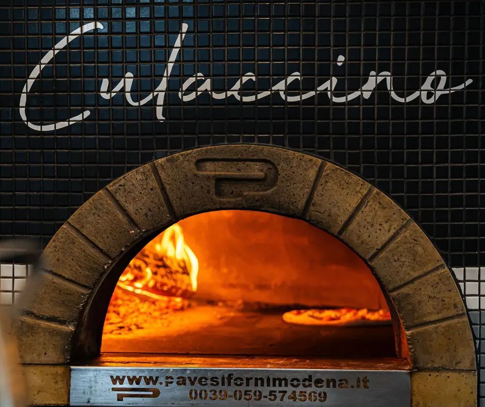 Culaccino's tiled wood-fired oven glowing with flame under the Culaccino script sign